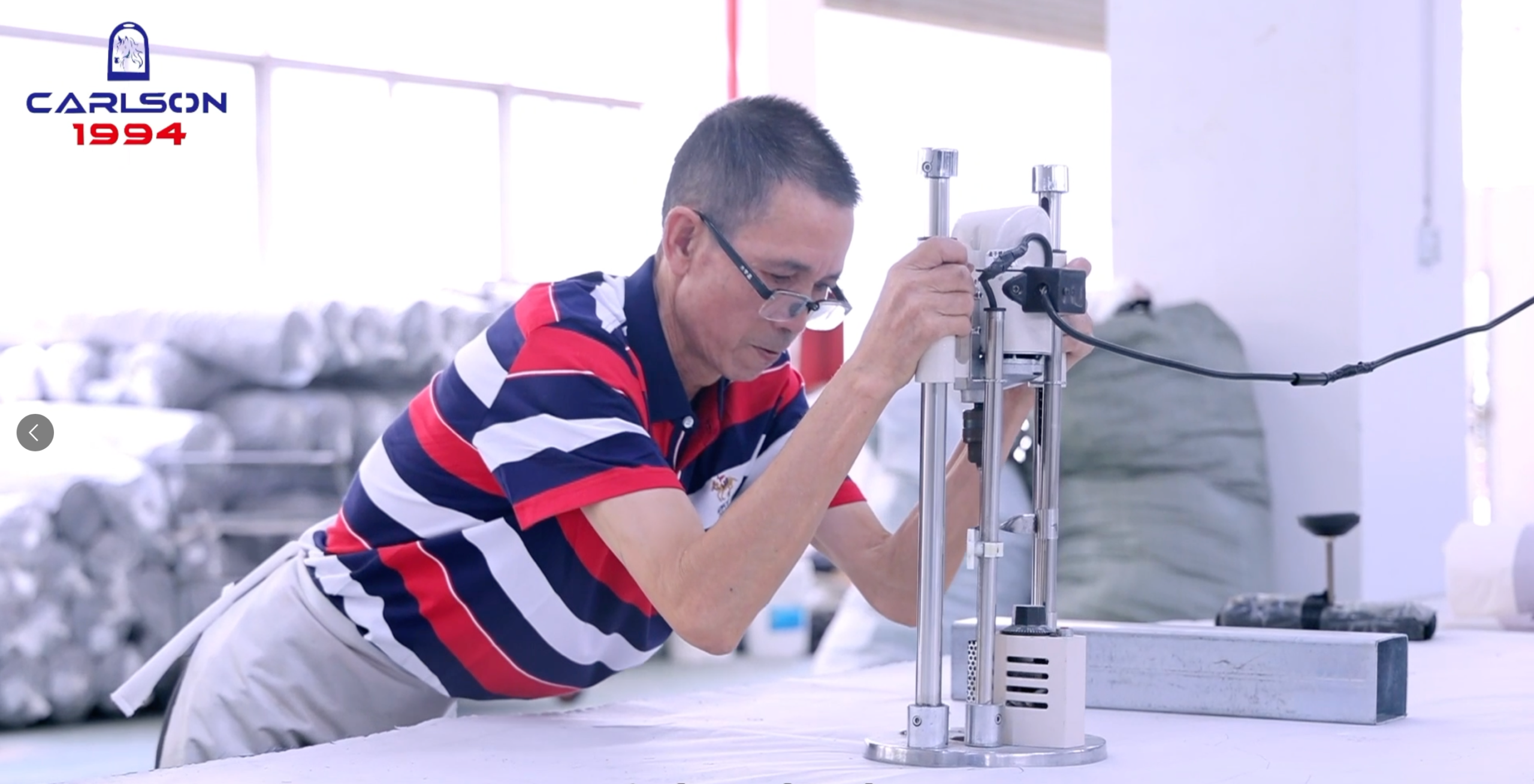 A senior technician at Carlson Saddlery using advanced fabric cutting and sampling machinery to inspect incoming material rolls for bulk equestrian products.